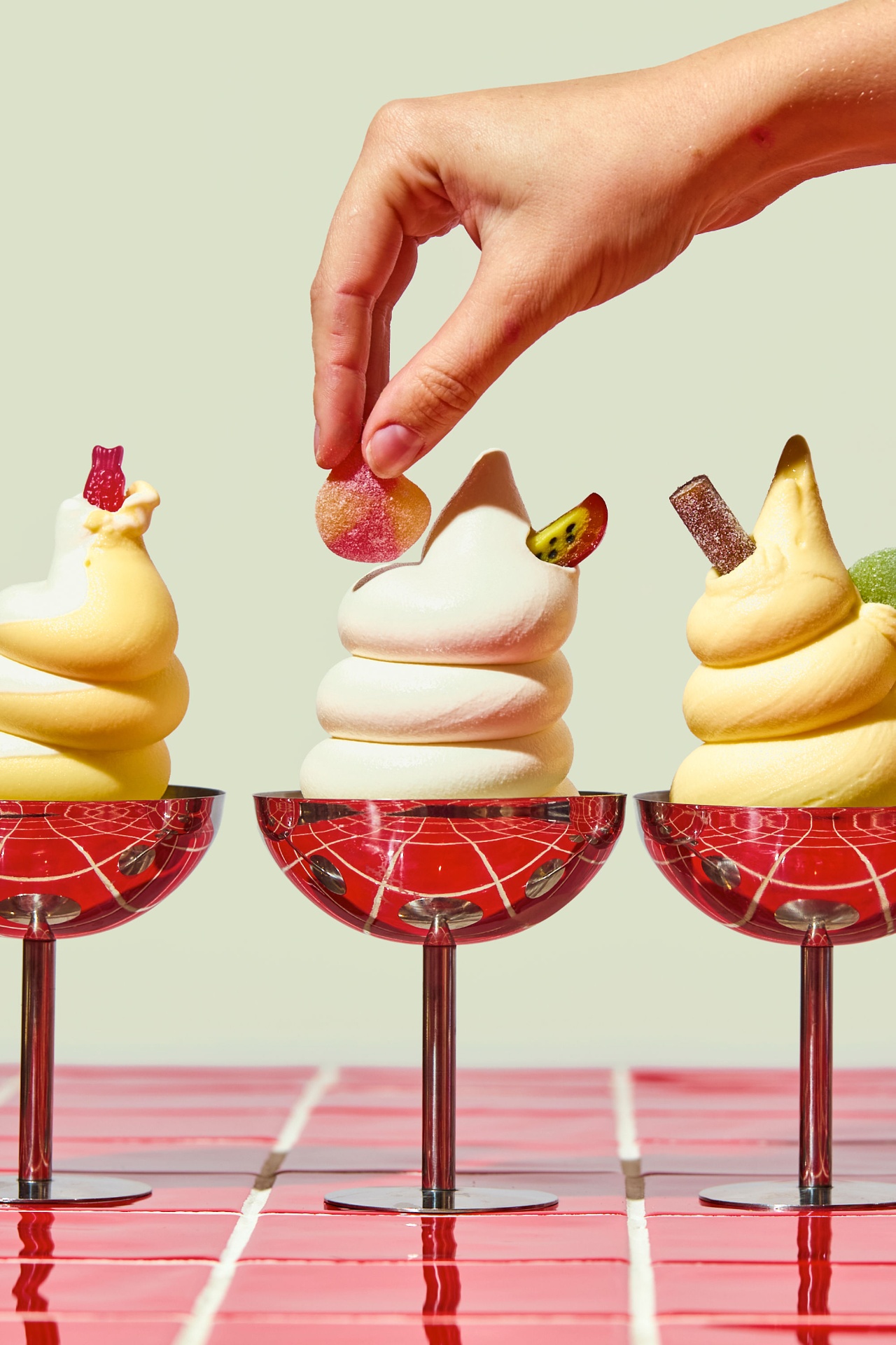 Three SLIK soft-serve desserts in metal jars topped with candy